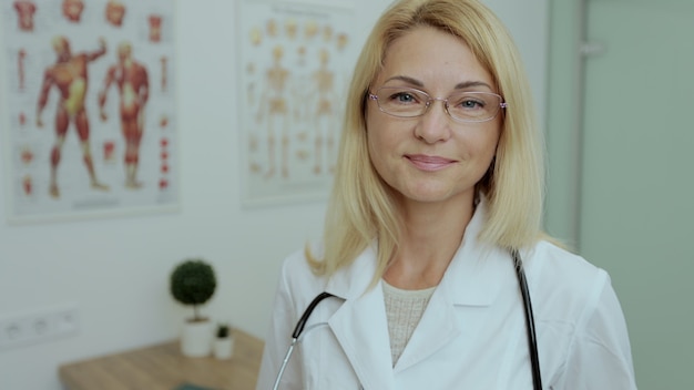 Bouchent le portrait d'une femme médecin avec des lunettes regardant la caméra de bonne humeur sur le lieu de travail. Concept de médecine, technologie, soins de santé et personnes, hôpital.