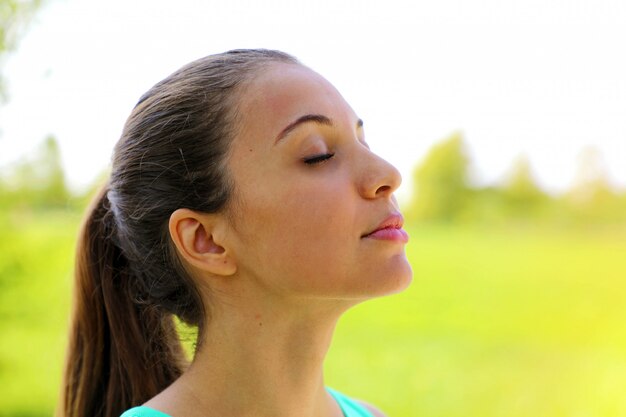 Bouchent le portrait de femme relaxante en respirant profondément l'air frais dans le parc.