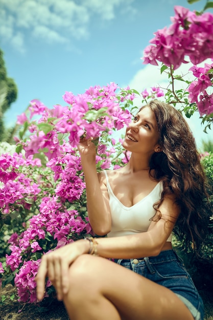 Photo bouchent portrait fille dans le parc sur fond de fleurs roses