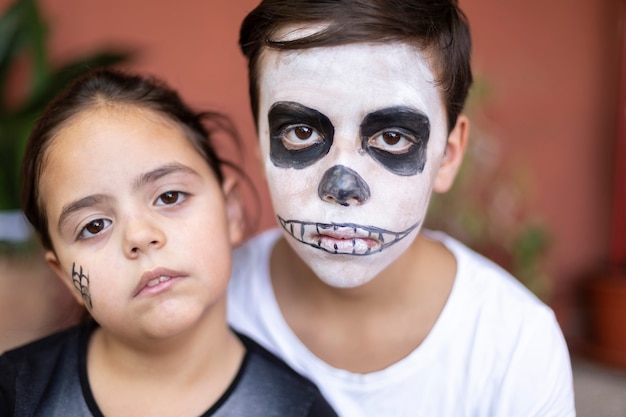 Bouchent le portrait d'un garçon caucasien et d'une petite fille maquillée pour le jour des morts. (Dia de los Muertos).