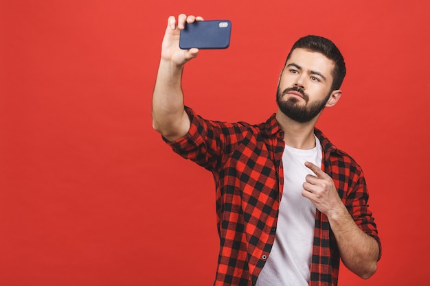 Bouchent le portrait d'un homme barbu sérieux prenant selfie sur mur rouge.