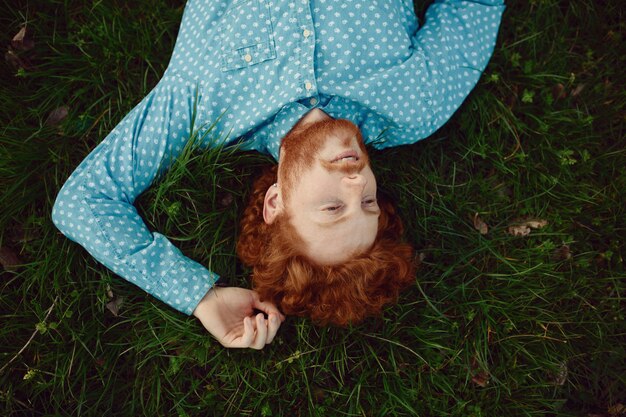Bouchent portrait homme rougeâtre bouclé couché sur l'herbe verte