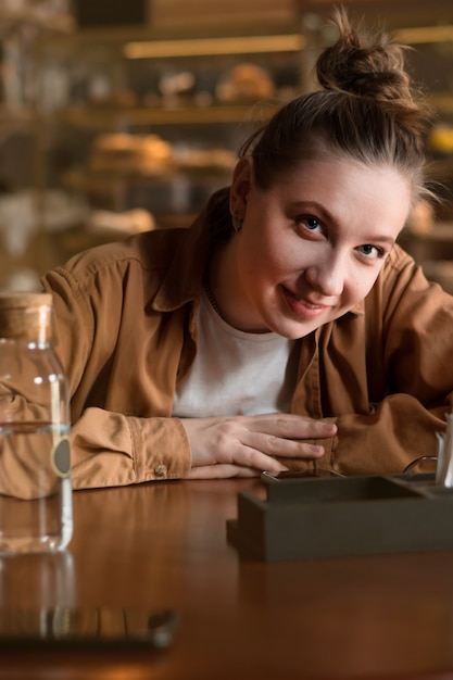 Bouchent portrait de jeune femme assise dans un café et regardant la caméra