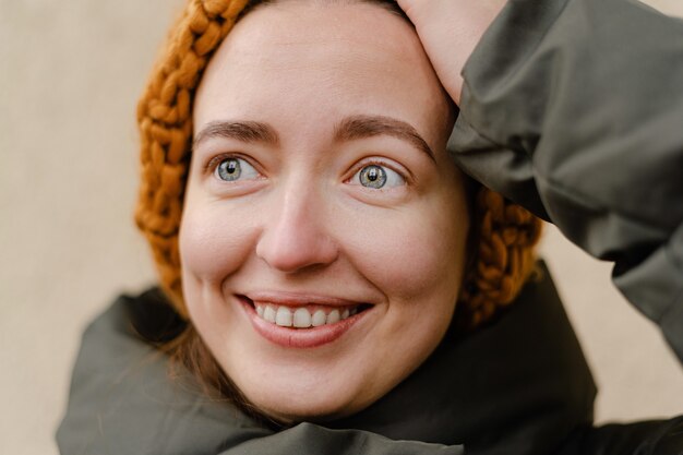 Bouchent le portrait de la jeune femme millénaire, heureuse et sortie à l'extérieur en tenue d'hiver. Étudiant