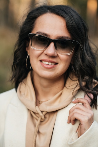 Bouchent le portrait de jeune fille brune à lunettes de soleil dans la forêt