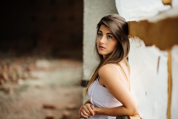 Bouchent le portrait de jeune jolie fille brune posée sur un lieu abandonné.