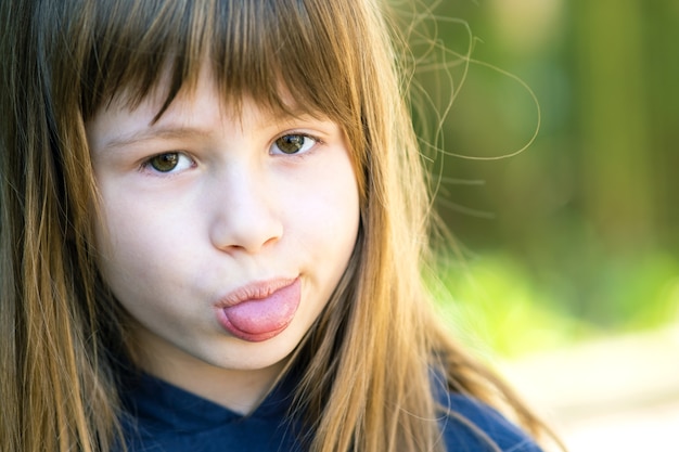 Bouchent le portrait d'une jolie fille montrant la langue et regardant la caméra.