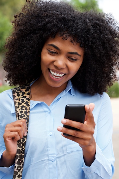 Bouchent portrait de joyeuse jeune femme afro-américaine à l&#39;extérieur avec un téléphone intelligent