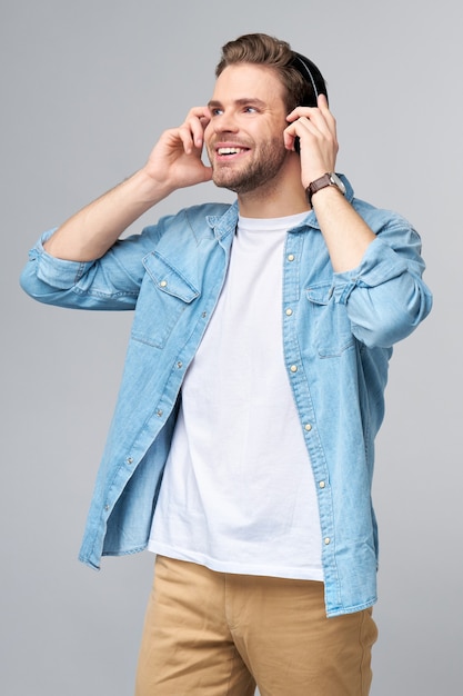 Bouchent le portrait de joyeux jeune homme appréciant écouter de la musique portant des jeans décontractés