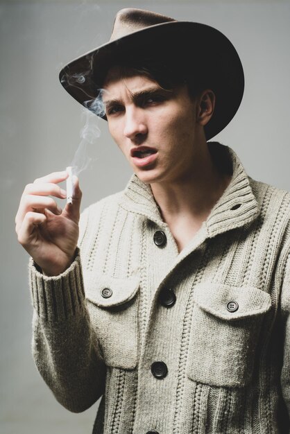 Photo bouchent le portrait d'un mec au chapeau de cowboy qui fume.