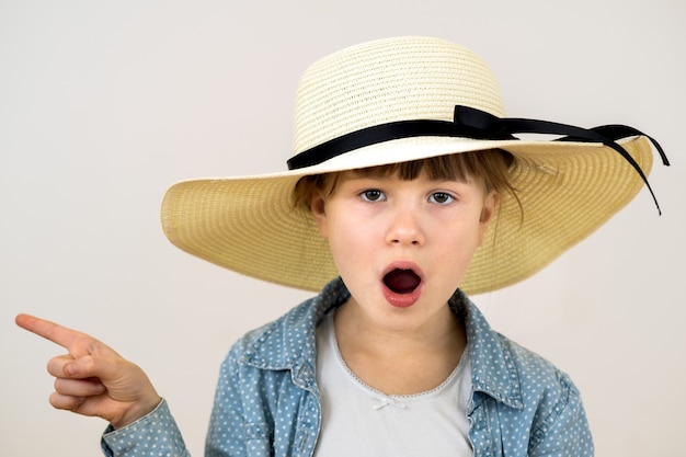 Bouchent le portrait d'une mignonne petite fille au chapeau beige avec une émotion surprise.