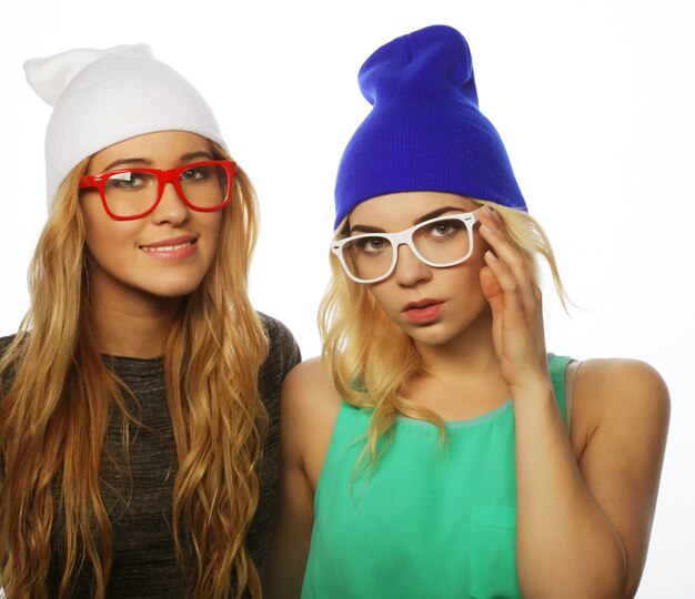 Bouchent le portrait de style de vie de deux jolies copines adolescentes souriantes et s'amusant, portant des vêtements hipster, des chapeaux et des lunettes, une humeur positive.