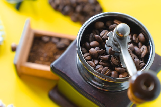 bouchent sélective vue de dessus grain de café dans une meuleuse manuelle en bois sur fond jaune