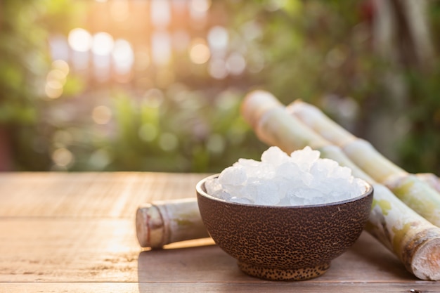 Bouchent le sucre de roche et la canne à sucre sur la table en bois avec fond de flou de la lumière du soleil