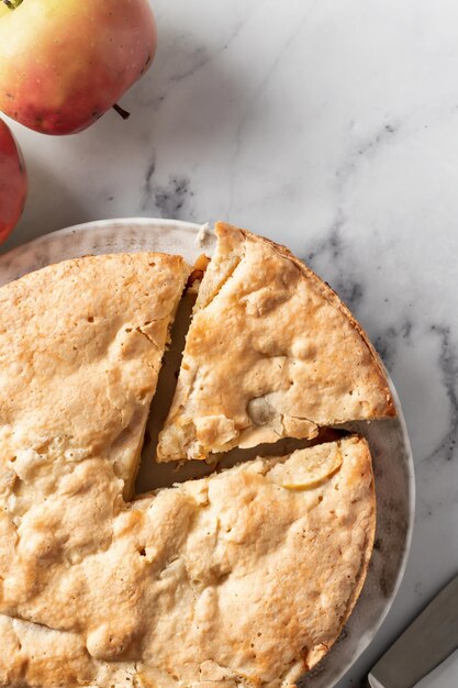 Bouchent la tarte aux pommes en tranches Charlotte aux pommes sur fond de marbre blanc vue de dessus mise à plat