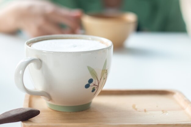 Bouchent une tasse de café latte chaud sur la table blanche