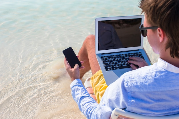 Photo bouchent le téléphone sur fond d'ordinateur à la plage