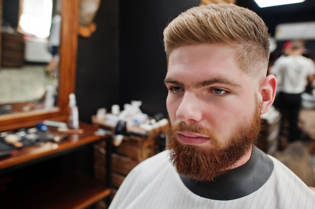 Bouchent la tête du jeune homme barbu se coupe les cheveux au salon de coiffure. Âme de coiffeur.