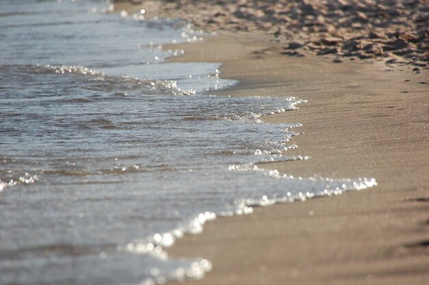 Bouchent les vagues d'eau de mer bleue sur la plage de sable.