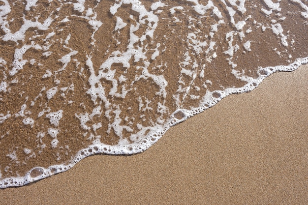 Bouchent les vagues d'eau de mer avec des bulles à la plage