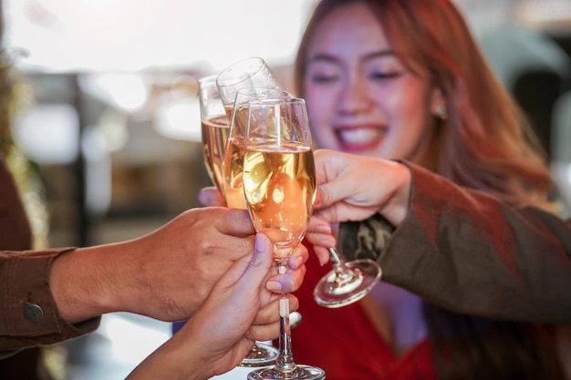 Bouchent les verres de verres de champagne tintants avec éclairage. Dîner avec consommation de champagne. les mains tenant un verre clair avec de l'alcool en jaune brillant se reflètent.