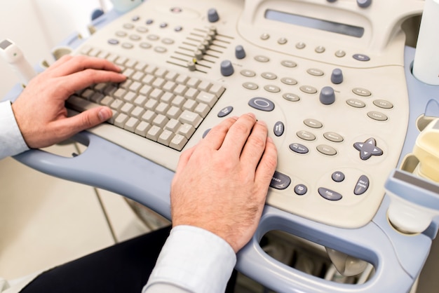 Bouchent la vue chez les mains de médecins travaillant sur le clavier ultrasons