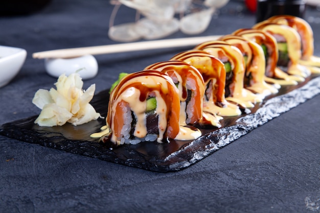 Bouchent la vue sur l'ensemble de rouleaux de sushi. Rouleau de Californie au saumon, avocat et caviar servi sur pierre noire à noir.