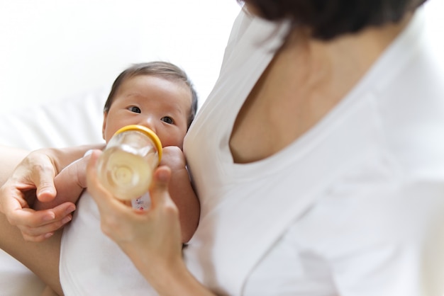 Bouchent la vue de la mère asiatique nourrir bébé de bouteille de lait.