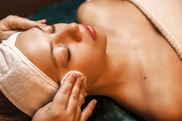 Bouchent la vue supérieure d'une charmante femme ayant une procédure de nettoyage de la peau dans un salon spa.