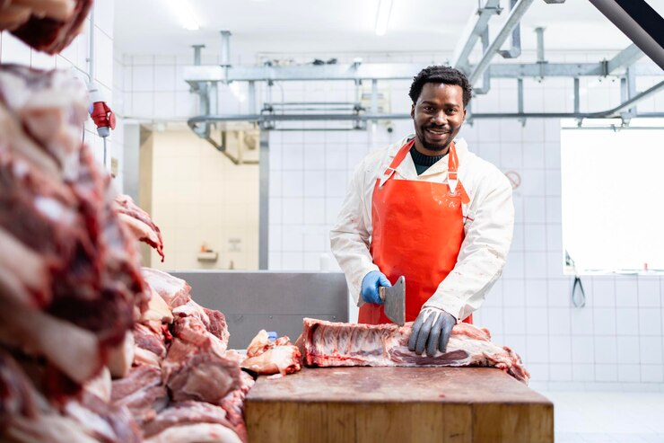 Un boucher afro-américain professionnel découpe de la viande de porc à l'intérieur d'un abattoir.