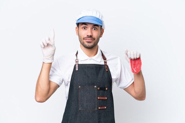 Boucher homme caucasien portant un tablier et servant de la viande fraîchement coupée sur fond blanc isolé pointant vers le haut une excellente idée