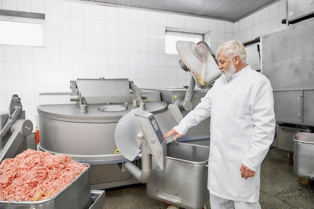 Boucher professionnel en uniforme près de l'équipement pour la viande.