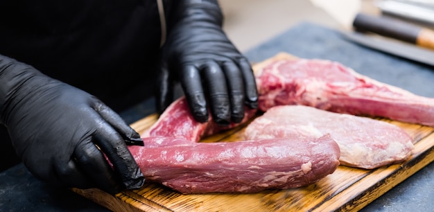 Boucherie. Coupes fraîches, assortiment de viande de bœuf cru sur planche de bois. Chef cuisinant des steaks.