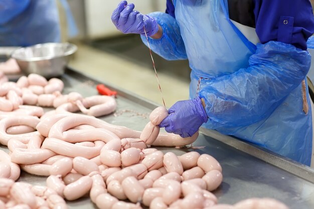 Boucheries préparant des saucisses dans une usine de viande.