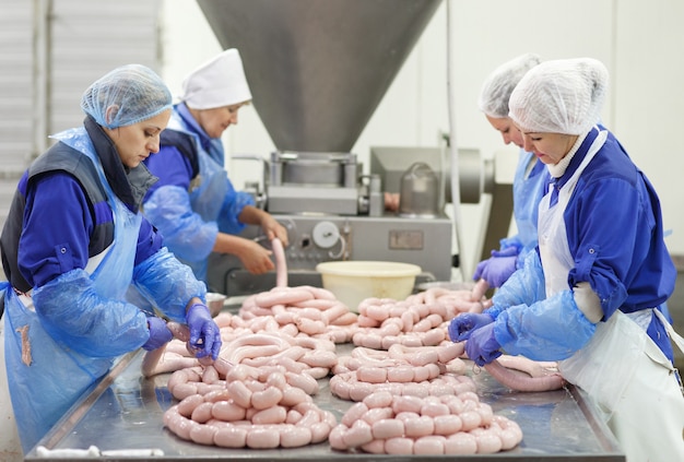 Boucheries préparant des saucisses dans une usine de viande.