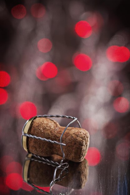 Bouchon de champagne sur la surface du miroir avec des lumières de bokeh rouge