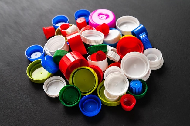 Bouchons de bouteilles en plastique recyclé Bouchons en PET de couleur sur fond noir Collecte séparée des déchets
