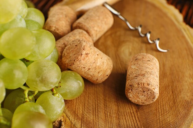 Bouchons de vin et tailspin avec grappe de raisin sur fond de bois