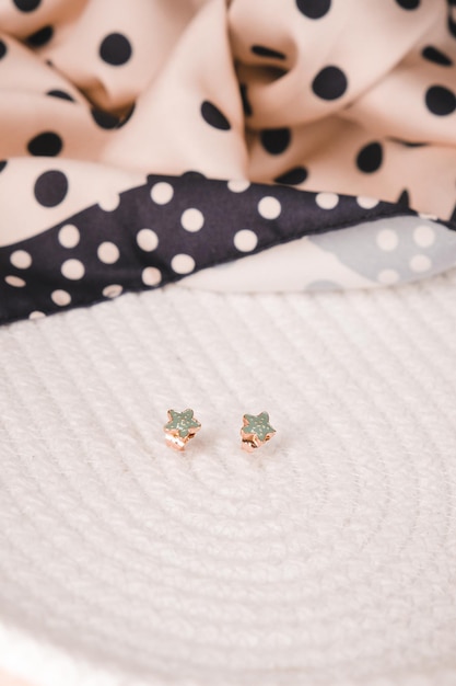 Des boucles d'oreilles en diamant vert reposent sur un fond à pois blancs et noirs.