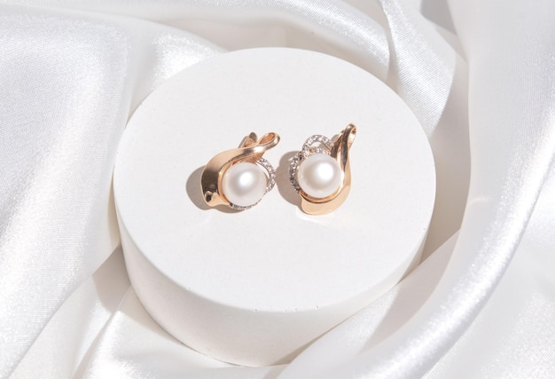 Boucles d'oreilles en perles avec garnitures dorées sur fond de soie blanche Beaux accessoires pour femmes Bijoux élégants cadeau ou cadeau pour mariage ou saint valentin