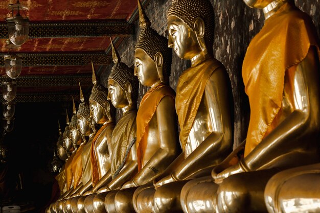 Bouddha doré à côté de vieux murs dans les temples thaïlandais
