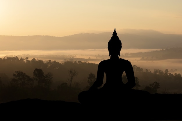 Bouddha de silhouette sur fond de coucher de soleil doré