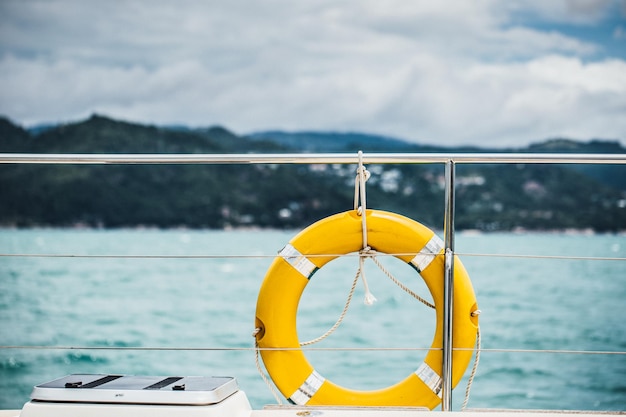 Bouée de sauvetage jaune en gros plan accrochée à un bateau avec un fond d'océan.