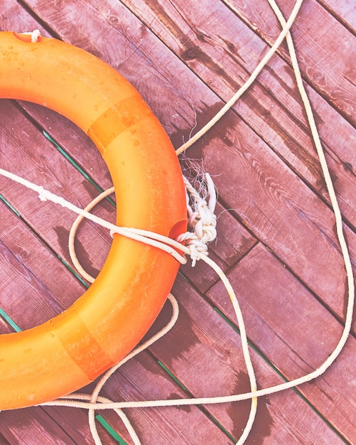 Bouée de sauvetage orange avec une corde sur une jetée en bois près de la mer.