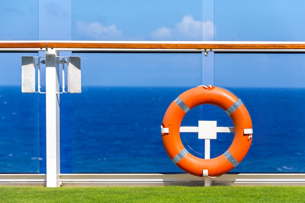 Bouée de sauvetage orange sur un pont de bateau de croisière avec océan sur fond avec ciel bleu et espace de copie