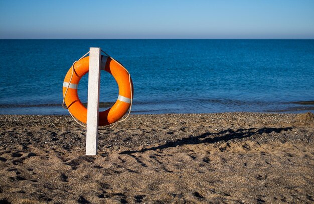 Bouée de sauvetage orange vif sur une plage de sable par une journée d'été ensoleillée