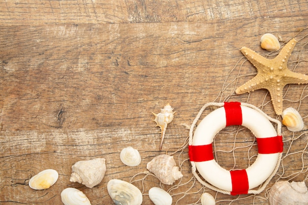 Bouée de sauvetage rouge-blanc avec sable et coquillages sur brun