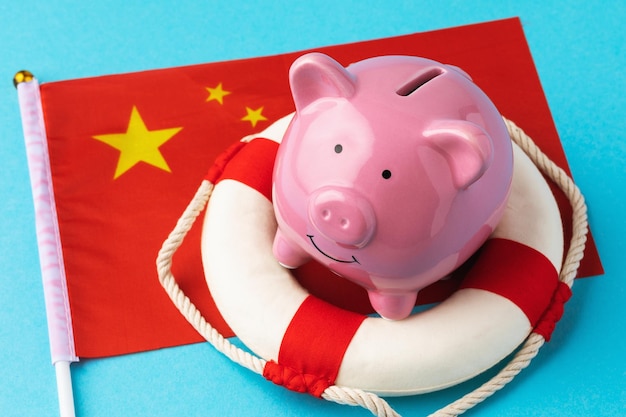 Bouée de sauvetage tirelire et drapeau sur fond coloré le concept de sauver l'économie chinoise