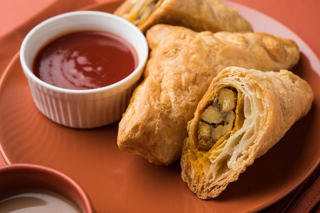 Photo bouffée de légumes farcis ou samosa, célèbre collation de boulangerie indienne, servie avec du ketchup aux tomates et du thé chaud, mise au point sélective