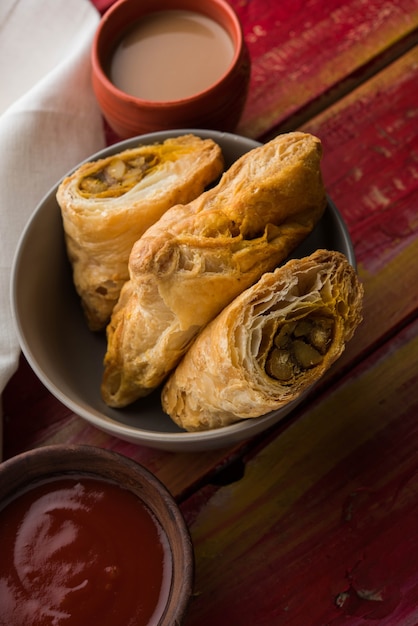 Bouffée de légumes farcis ou samosa, célèbre collation de boulangerie indienne, servie avec du ketchup aux tomates et du thé chaud, mise au point sélective